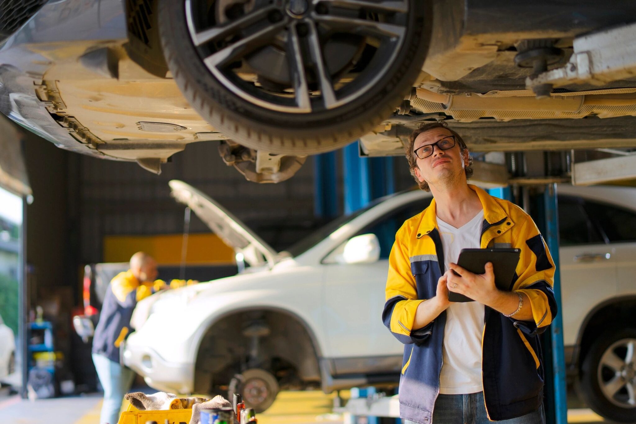 Mechanic inspecting car underside in garage.